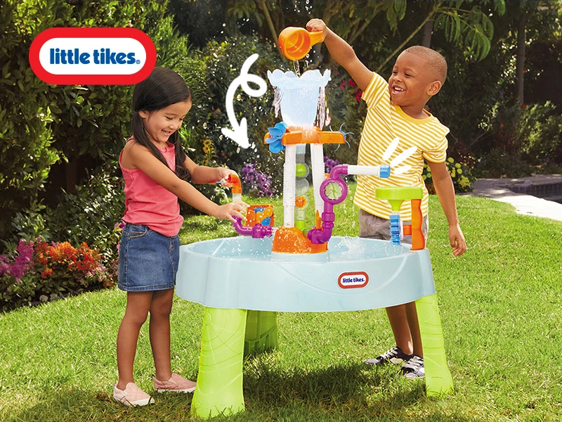 Two children joyfully play with a Little Tikes water table in a sunny garden.